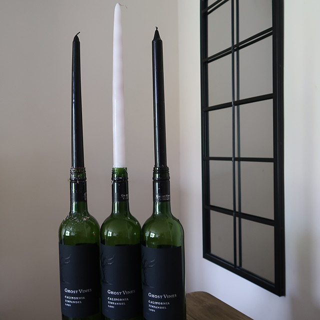 The three varieties of dripping taper candle in wine bottles, in front of a mirror