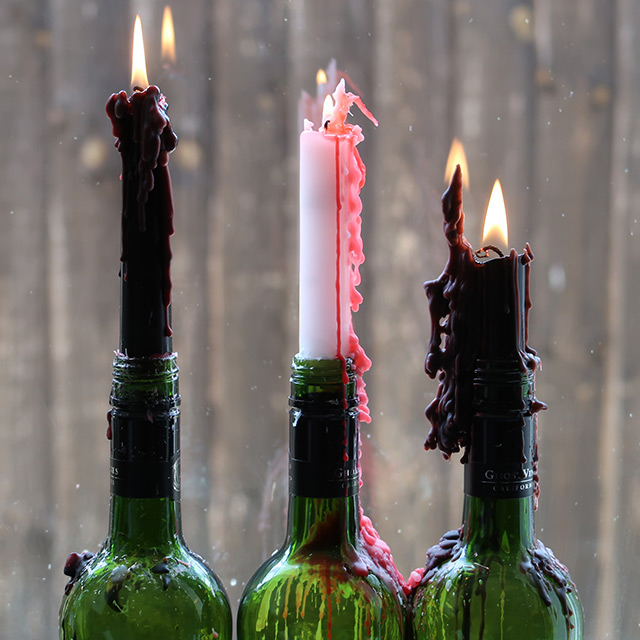 The three varieties of dripping taper candle in wine bottles, lit and quite melted
